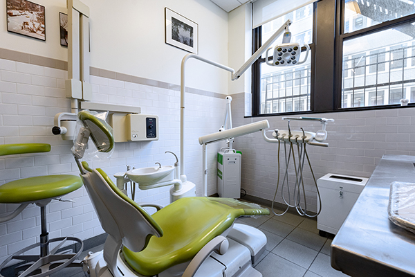The image depicts a dental office with a clean, modern appearance, featuring multiple chairs and equipment.