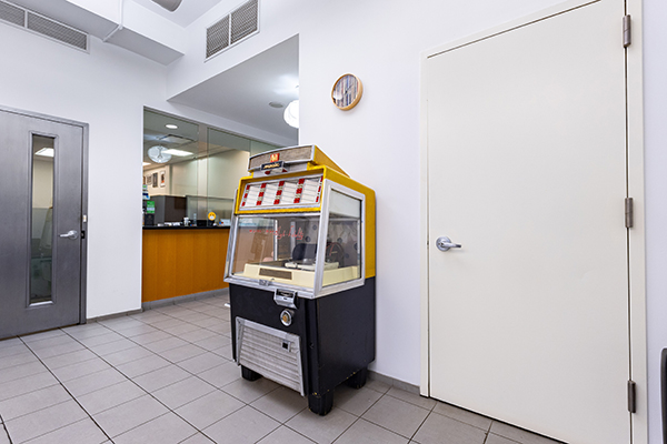 An interior view of a room with a gaming machine, a door, and an illuminated sign on the ceiling.