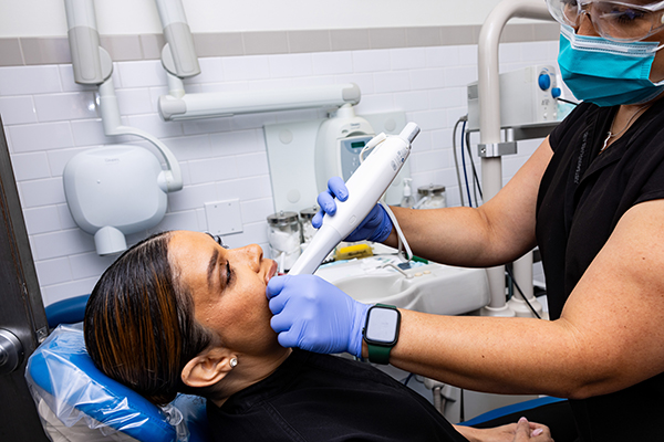 A healthcare professional using a dental device on a patient in a dental office.