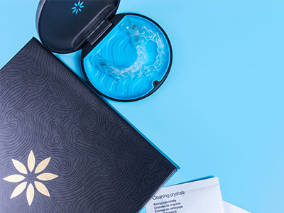 A blue toothbrush and a black box with a floral design on a light blue surface.